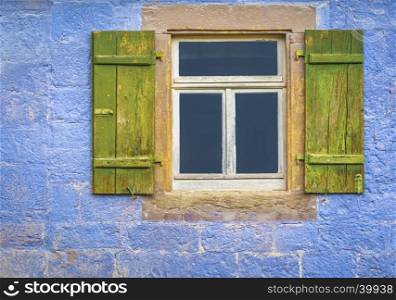 Architectural details over a window with wooden shutters, from an antique german house with walls painted in blue.