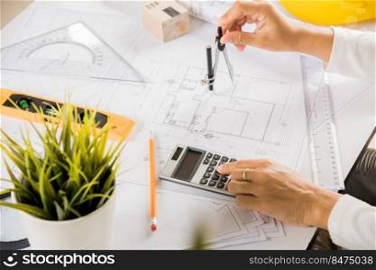 Architectural project workplace. Engineer sketching construction project, Architect drawing with divider compass on house plan blueprint paper for repair tools on table desk at architecture office