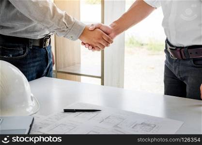 architecture and home renovation concept - builder with blueprint shaking partner hand in retro style.