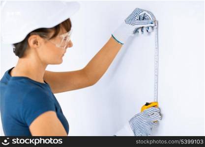 architecture and home renovation concept - female architect measuring wall with flexible ruller