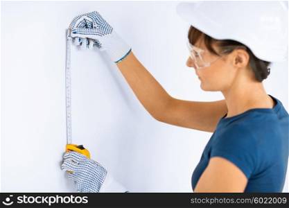 architecture and home renovation concept - female architect measuring wall with flexible ruller. architect measuring wall with flexible ruller