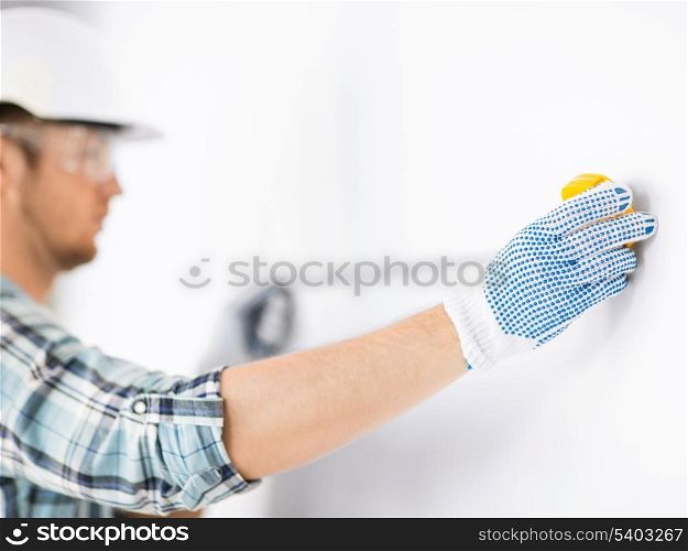 architecture and home renovation concept - male architect measuring wall with flexible ruler