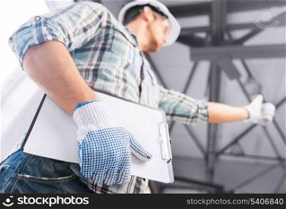 architecture and home renovation concept - man in helmet and gloves with blueprint in factory