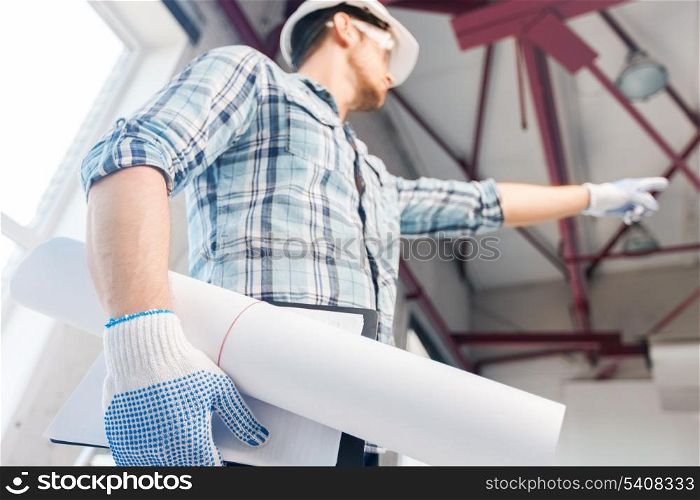 architecture and home renovation concept - man in helmet and gloves with blueprint showing direction