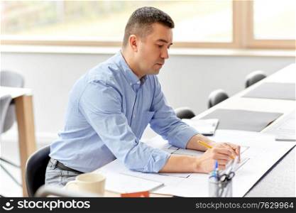 architecture, building, construction and real estate concept - middle-aged male architect with blueprint, ruler and living house model on table working at home office. architect with blueprint working at home office