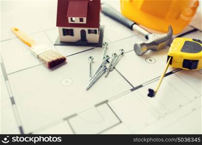 architecture, building, construction, real estate and home concept - close up of living house model on blueprint with repair tools. close up of house blueprint with building tools