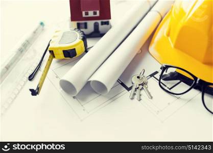 architecture, building, construction, real estate and home concept - close up of architectural blueprint with tools and house keys. close up of blueprint with tools and house keys