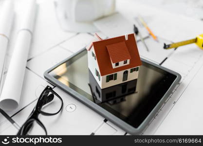 architecture, building, construction, real estate and home concept - close up of living house model on tablet pc computer screen