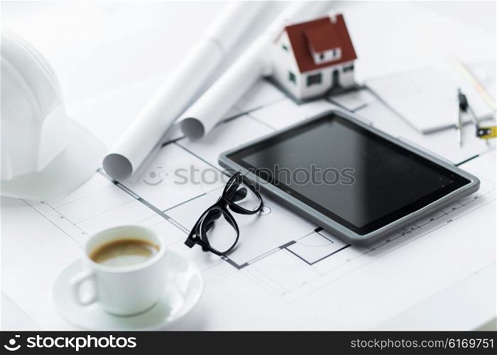architecture, building, construction, real estate and home concept - close up of living house model and tablet pc computer screen at office