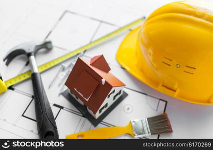 architecture, building, construction, real estate and home concept - close up of living house model on blueprint with repair tools