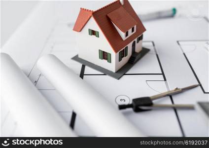 architecture, building, construction, real estate and home concept - close up of living house model and compass on blueprint