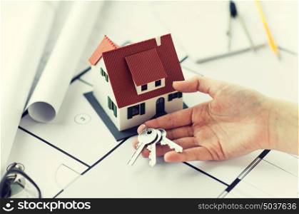 architecture, building, construction, real estate and home concept - hand with house keys and blueprint. close up of hand with house keys and blueprint