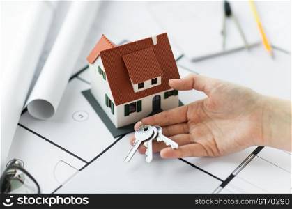 architecture, building, construction, real estate and home concept - hand with house keys and blueprint