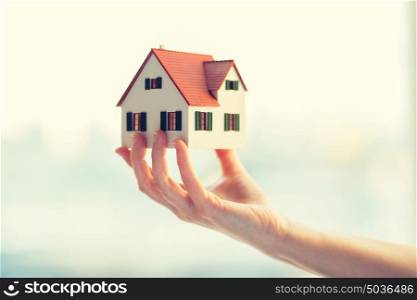 architecture, building, construction, real estate and property concept - close up of hands holding house or home model. close up of hands holding house or home model