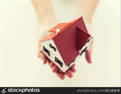 architecture, building, construction, real estate and property concept - close up of hands holding house or home model. close up of hands holding house or home model