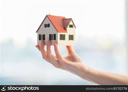 architecture, building, construction, real estate and property concept - close up of hands holding house or home model