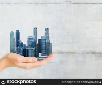 architecture, building, urban and people concept - hand holding city over gray concrete background. hand holding city over gray concrete background