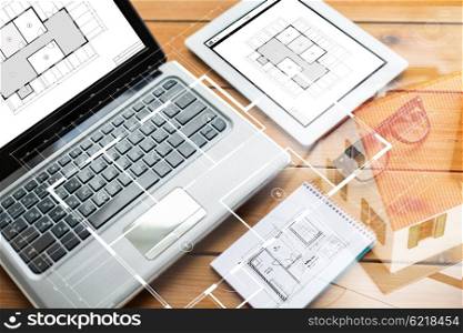 architecture, business and technology concept - close up of on laptop computer, tablet pc, notebook and eyeglasses with blueprint of room on wooden table