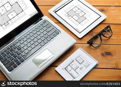 architecture, business and technology concept - close up of on laptop computer, tablet pc, notebook and eyeglasses with blueprint of room on wooden table