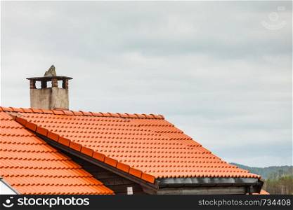 Architecture concept. Dutch red roof of house with concrete chimney, cloudy sky in background. Red roof of house with concrete chimney
