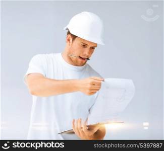 architecture concept - male architect in helmet looking at blueprint