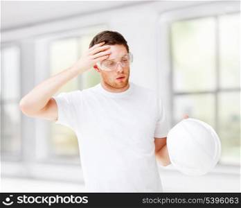 architecture concept - male architect in safety glasses taking off helmet