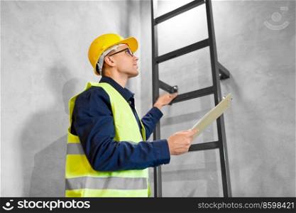 architecture, construction and building concept - male builder or worker in helmet and safety west with clipboard climbing ladder or stairs. builder or worker with clipboard at ladder