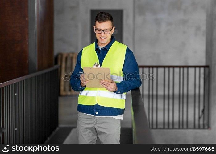 architecture, construction business and building concept - happy smiling male architect in safety west with clipboard working at office. male architect with clipboard at office