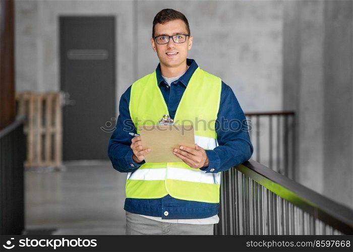 architecture, construction business and building concept - happy smiling male architect in safety west with clipboard working at office. male architect with clipboard at office