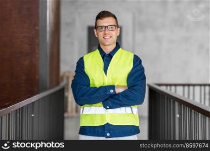 architecture, construction business and building concept - happy smiling male architect in safety west at office. male architect in safety west at office