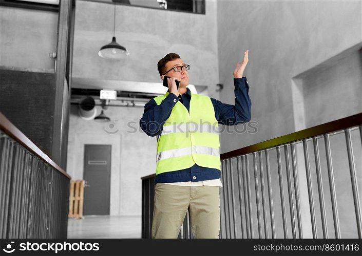architecture, construction business and building concept - male supervisor in safety west calling on smartphone at office. male supervisor calling on smartphone at office