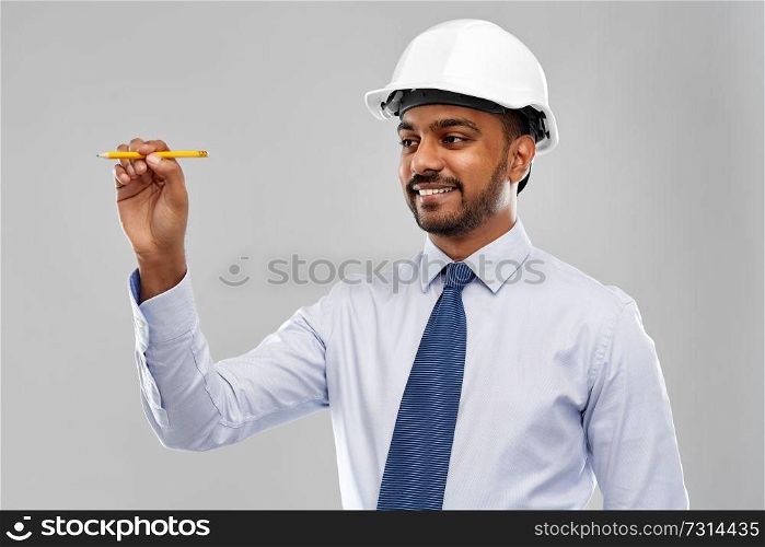 architecture, construction business and building - smiling indian architect or businessman in helmet with pencil drawing something imaginary over grey background. indian architect or businessman in helmet