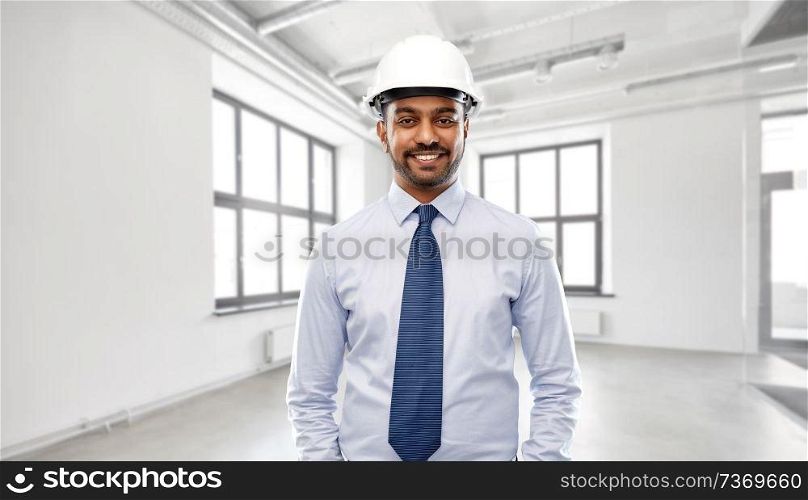 architecture, construction business and building - smiling indian architect or businessman in helmet over empty room background. indian architect or businessman in helmet