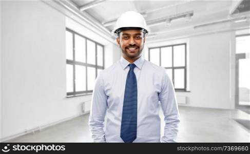 architecture, construction business and building - smiling indian architect or businessman in helmet over empty room background. indian architect or businessman in helmet
