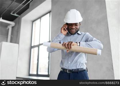 architecture, construction business and people concept - african american architect in helmet with blueprint calling on smartphone and looking at his wristwatch. architect with blueprint calling on smartphone. architect with blueprint calling on smartphone