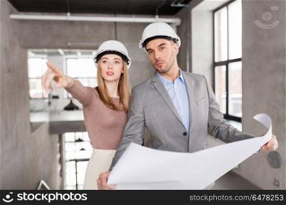 architecture, construction business and people concept - architects with blueprint and helmets at office pointing at something. architects with blueprint and helmets at office. architects with blueprint and helmets at office