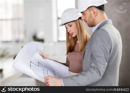 architecture, construction business and people concept - architects with blueprint and helmets at office. architects with blueprint and helmets at office