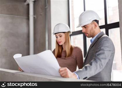 architecture, construction business and people concept - architects with blueprint and helmets at office. architects with blueprint and helmets at office. architects with blueprint and helmets at office