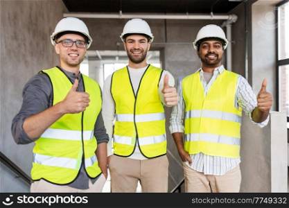 architecture, construction business and people concept - happy smiling male architects in helmets showing thumbs up at office. happy male architects showing thumbs up at office