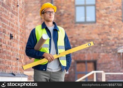 architecture, construction business and people concept - male architect or builder in helmet and safety west with level and blueprint on site. male architect in helmet with level on site