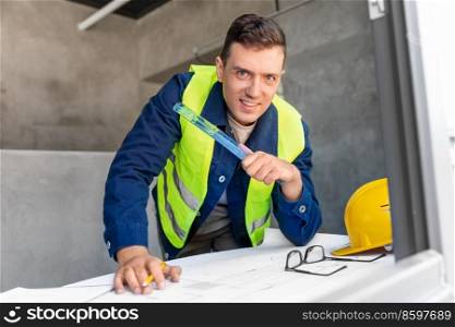 architecture, construction business and people concept - male architect with blueprint and ruler working at office. male architect with blueprint and ruler at office