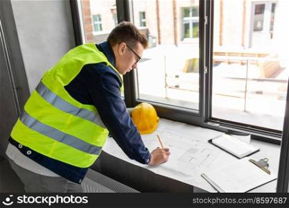 architecture, construction business and people concept - male architect with blueprint working at office. male architect with blueprint working at office