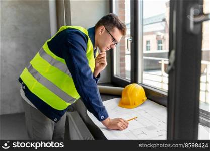 architecture, construction business and people concept - male architect with blueprint working at office. male architect with blueprint working at office