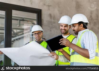 architecture, construction business and people concept - male architects in helmets with blueprint working in office building. architects with blueprint in office building