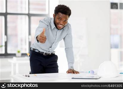 architecture, construction business and people concept - smiling african american architect with blueprint working at office and showing thumbs up. african architect with blueprint showing thumbs up. african architect with blueprint showing thumbs up