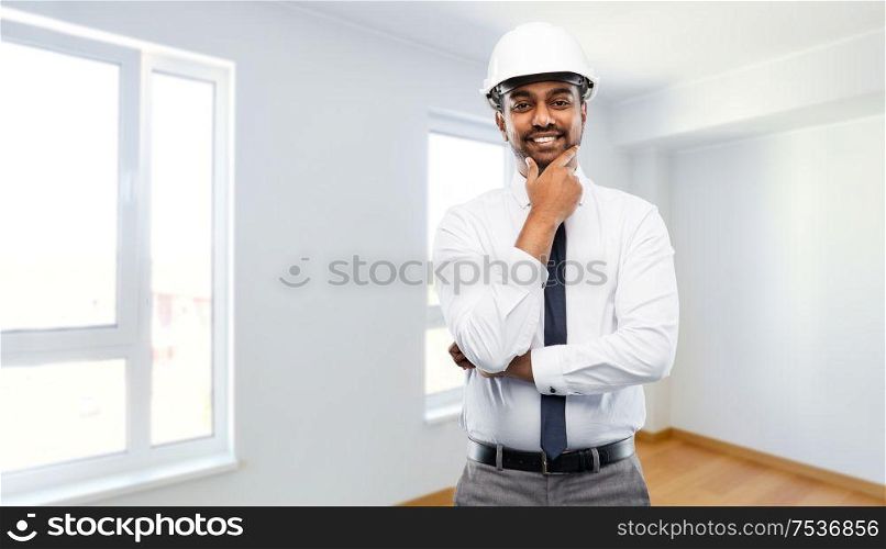 architecture, construction business and people concept - smiling indian male architect in helmet over empty new apartment room background. indian male architect in helmet at new apartment