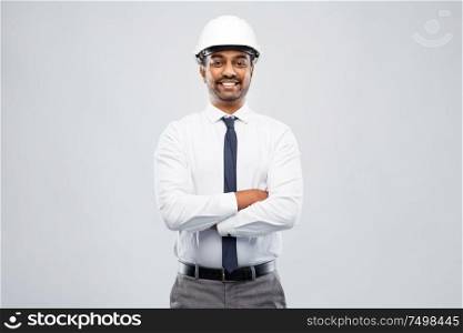 architecture, construction business and people concept - smiling indian male architect in helmet over grey background. smiling indian male architect in helmet over grey