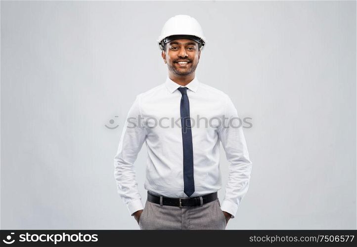 architecture, construction business and people concept - smiling indian male architect in helmet over grey background. indian male architect in helmet over grey