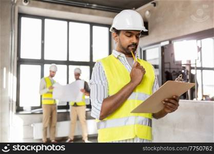 architecture, construction business and people concept - thinking male architect in helmet with clipboard and pencil at office. male architect with clipboard and pencil at office