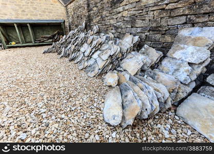 Architecture detail. Old stone house with stack of roof tiles, village Bibury, England